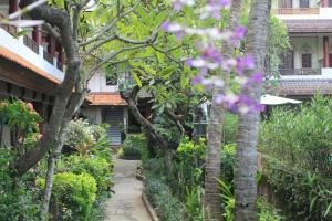 une passerelle traversant un jardin planté d'arbres et de fleurs dans l'établissement Bakung Sari Resort and Spa, à Kuta