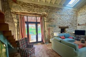 un soggiorno con divano blu e parete in pietra di La Cabaña San Pelayo a San Pelayo - Merindad de Montija