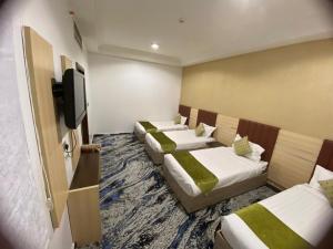 a hotel room with four beds and a flat screen tv at فندق عبدالملك الششة in Miná