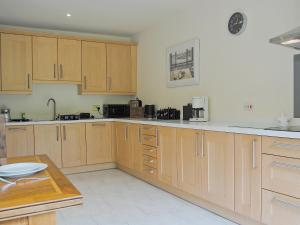 Una cocina grande con gabinetes de madera y una mesa. en Hendre Barn Mawr, en Abergynolwyn