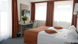 a hotel room with a bed and a desk and windows at Komfort Hotel Ludwigsburg in Ludwigsburg