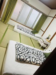 two beds in a room with a window at Nippori Osaka Nishi-Tengachaya Guesthouse西天下茶屋アパートメント in Osaka