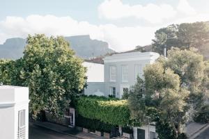 a white house with trees and mountains in the background at Cape Finest - De Waterkant House in Cape Town +26 photos