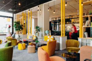 a lobby with yellow and orange chairs and tables at PlanB - Living Saint-Gervais - 250m des Remontées Mécaniques in Saint-Gervais-les-Bains