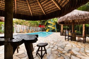 a patio with a table and chairs and a swimming pool at Pousada Camury in Garuva