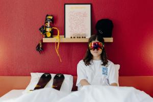 a young girl wearing sunglasses sitting on a bed at PlanB - Living Saint-Gervais - 250m des Remontées Mécaniques in Saint-Gervais-les-Bains
