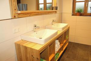 a bathroom with two sinks on a wooden counter at Ferienwohnung Hutter in Fischen +14 photos