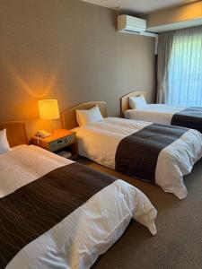 Una habitación de hotel con dos camas y una lámpara. en GLOBAL RESORT NUKUI, en Akiota