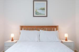 a bedroom with a white bed with two lamps at 2-bedroom apartment in Headington with free parking, walking distance to Oxford Hospitals & Brookes Uni in Oxford