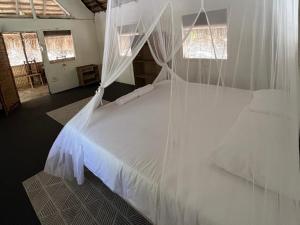 a bedroom with a white bed with mosquito netting at Mango Beach Resort in Praia do Tofo +65 photos