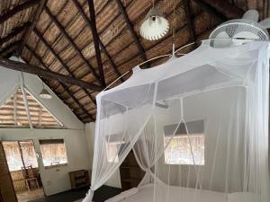 a bedroom with a bed with white mosquito nets at Mango Beach Resort in Praia do Tofo