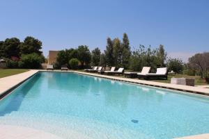 a large swimming pool with lounge chairs in a yard at Terre Di Vendicari in Noto