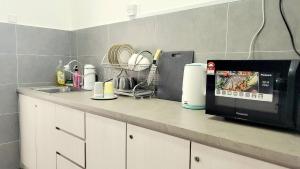 a kitchen counter with a microwave and a sink at Ipoh Cove Hillside Mini Waterpark Family Suite in Ipoh