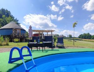 a pool with chairs and a gazebo at Glamping Pogorzany - Jurty in Zabierzów