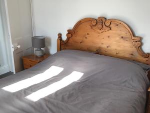 Una cama con cabecero de madera en un dormitorio. en Barreg, en Barmouth 14 fotos más