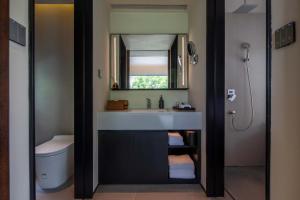 ein Badezimmer mit Waschbecken, Toilette und Spiegel in der Unterkunft Mucheng Xichi Snow Mountain Art Resort Hotel (Baisha Ancient Town Branch) in Lijiang + 134 Fotos