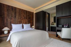 ein Schlafzimmer mit einem großen weißen Bett und einem Stuhl in der Unterkunft Mucheng Xichi Snow Mountain Art Resort Hotel (Baisha Ancient Town Branch) in Lijiang