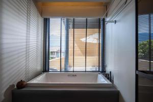 eine Badewanne im Bad mit Fenster in der Unterkunft Mucheng Xichi Snow Mountain Art Resort Hotel (Baisha Ancient Town Branch) in Lijiang