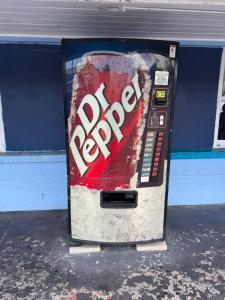 a soda machine with a sign on the side of it at Antigua Motel by OYO Tampa US - 41 in Tampa