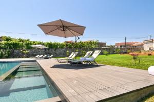 eine Terrasse mit Stühlen und einem Sonnenschirm sowie ein Pool in der Unterkunft Casas D'Além Refuge with Pool & Nature by Sé Apartamentos in Calvos