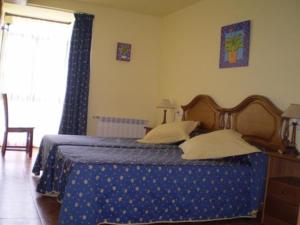 a bedroom with a bed with a blue blanket and a window at Casa de Aldea Ruiloba in Camango