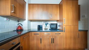 a kitchen with wooden cabinets and a microwave at Cosy Flat in the Heart of Greenwich in London