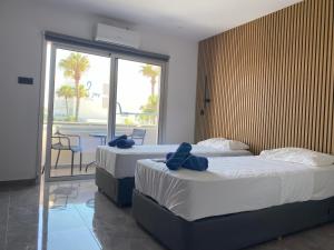 two beds in a hotel room with a balcony at Nissi Avenue Studios in Ayia Napa