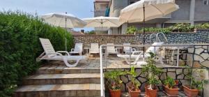a patio with white chairs and tables and umbrellas at Family hotel Favourite in Obzor