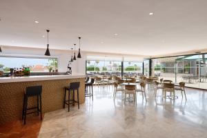 a restaurant with a bar with chairs and tables at Alua Illa de Menorca in S'Algar