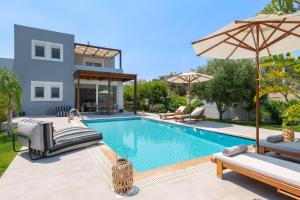 a swimming pool with chairs and an umbrella next to a house at Villa Olvia in Gennadi
