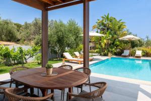 a patio with a wooden table and chairs and a swimming pool at Villa Olvia in Gennadi +20 photos