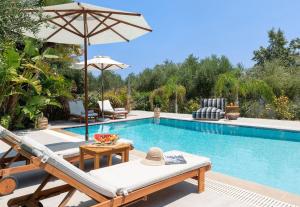 a swimming pool with a patio furniture and an umbrella at Villa Olvia in Gennadi