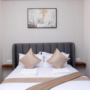 SkyView Haven by Seluveto Homes في نيروبي: غرفة نوم بها سرير مع ملاءات ووسائد بيضاء