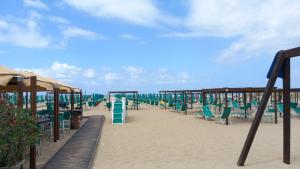 una playa con sillas y sombrillas en la arena en La casa di nonna Lina al mare - senza barriere, en Torre del Lago Puccini