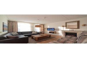 a living room with a couch and a fireplace at Holiday home with whirlpool and sauna in a quiet area in Zeeland in Colijnsplaat