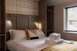 a bedroom with a bed with a pile of towels at The Crown & Horns in Newbury