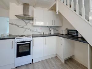 a kitchen with white cabinets and a staircase at York Road in Great Yarmouth +7 photos