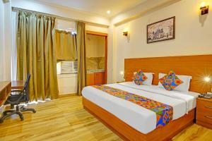 a hotel room with a bed and a desk and a window at FabHotel The Viraaj in Noida