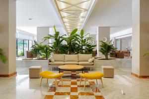 a lobby with a couch and a table and chairs at Alua Illa de Menorca in S'Algar