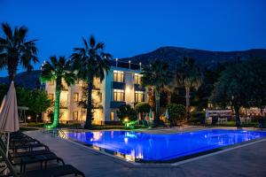 a swimming pool with palm trees and a building at Carrington Suites in Oludeniz