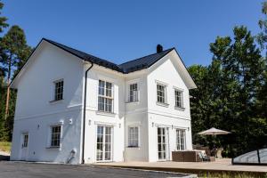 a white house with a black roof at Villa Svinninge in Åkersberga