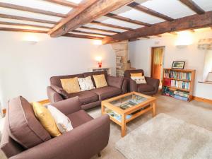 Una sala de estar con dos sofás y una mesa de café. en Trickett Gate Cottage, en Castleton