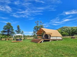 a large building with a tent in a field at Veselia Glamping in Valea Drăganului