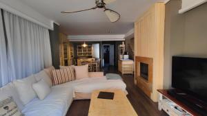 ein Wohnzimmer mit einem weißen Sofa und einem Fernseher in der Unterkunft Velvet Pines Villa, Elani by Halkidiki Villas in Elani