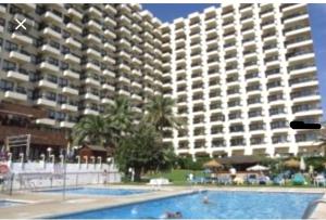a large apartment building with a pool in front of it at Aloha 1º linea playa Benalmadena in Benalmádena