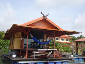a house on a boat with a hammock on the water at Hidden Holiday House in Ban Don Faek