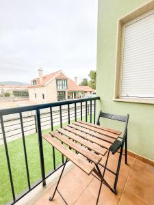 un banco de madera en un balcón con vistas a una casa en Apto MN Langosteira by ALÔGA, en Finisterre