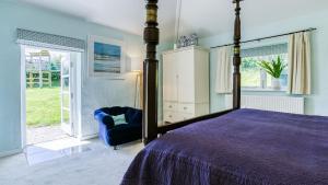 a bedroom with a canopy bed and a blue chair at Ty Siam in Newborough