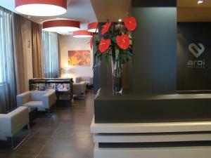 a waiting room with a vase of red flowers on a counter at Hotel Aroi Ponferrada in Ponferrada