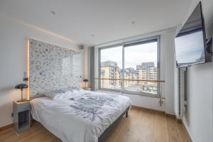 a bedroom with a bed and a large window at Le penthouse des ours in Courseulles-sur-Mer